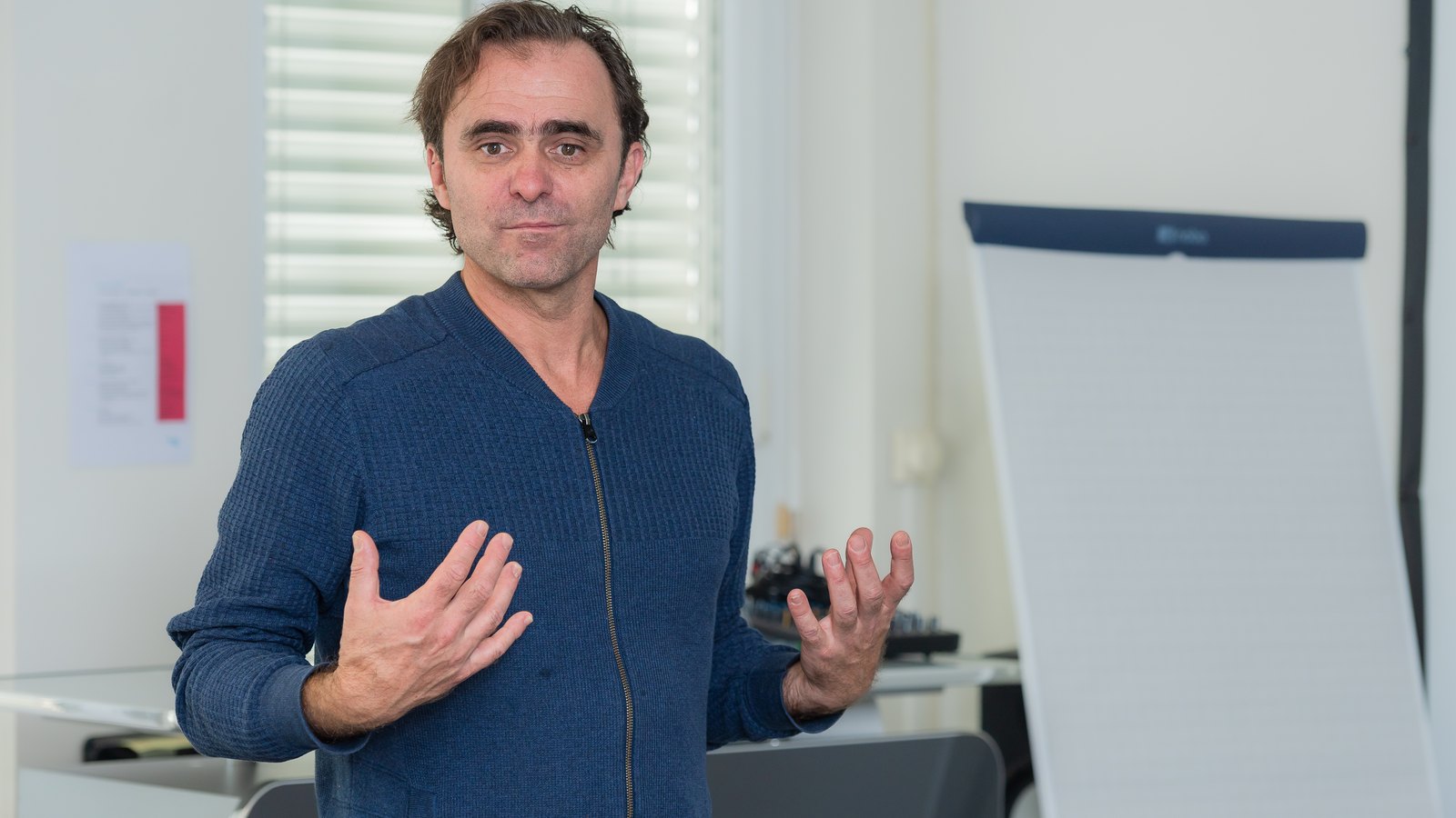 Roman Weber erklärt mit offenen Händen vor einem Flipchart.